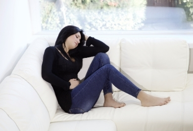 mujer sentada en sofa con la mano en el vientre